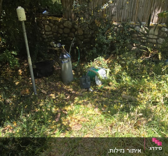 ציוד גינון וצינורות בגינה עם צמחייה